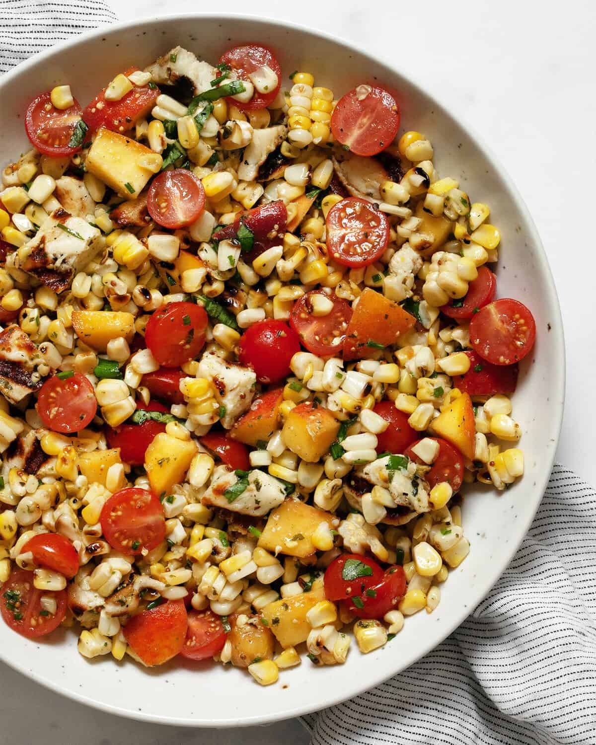 Grilled halloumi salad with corn, tomatoes and peaches in a bowl.