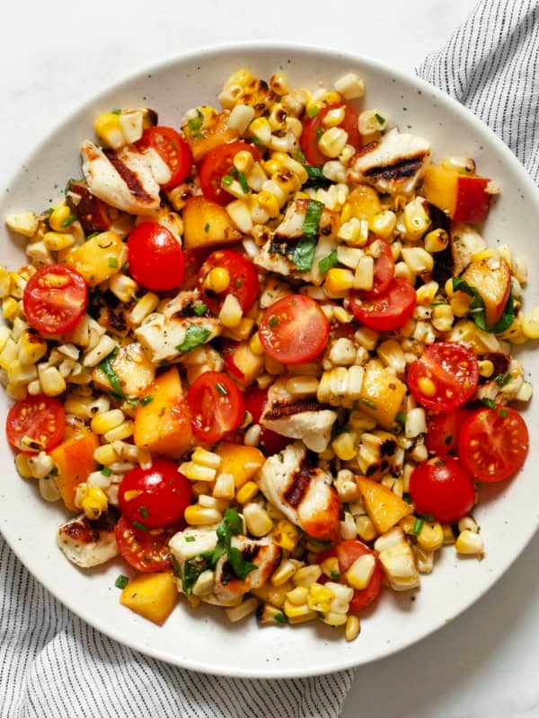 Grilled halloumi salad with corn, tomatoes and peaches on a plate.