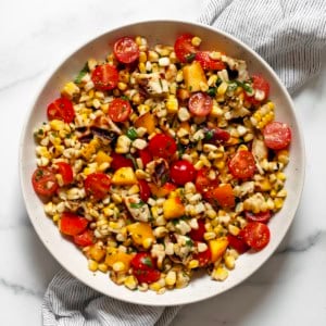 Grilled halloumi salad with corn, tomatoes and peaches in a bowl.