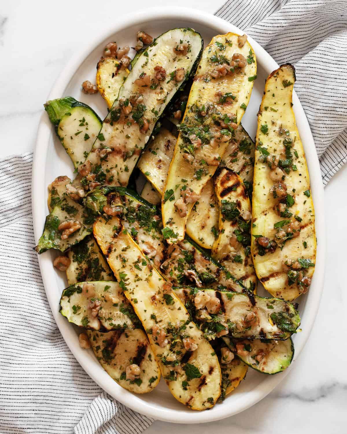 Grilled zucchini and squash on an oval serving plate.