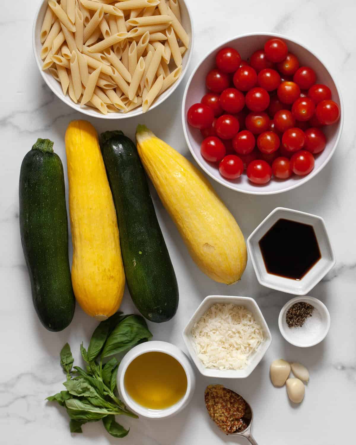 Ingredients including zucchini, squash, tomatoes, penne, garlic, olive oil, balsamic vinegar, parmesan, basil, mustard, salt and pepper.