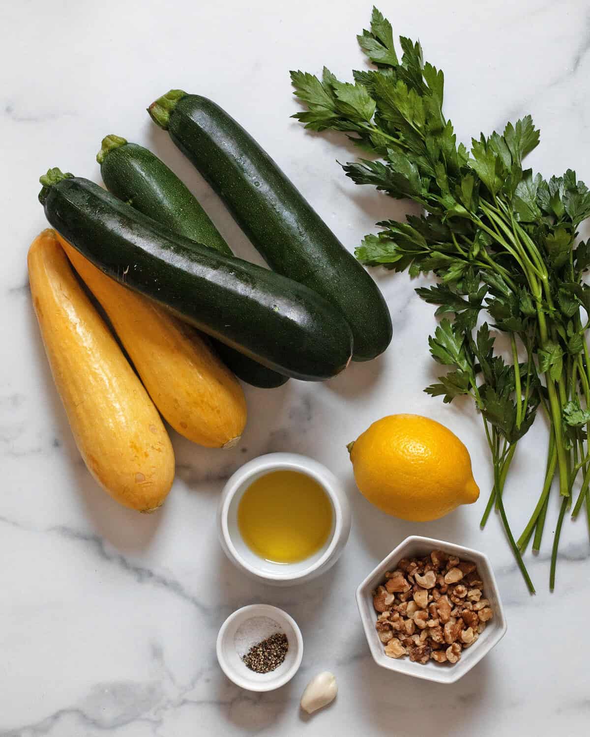 Ingredients including zucchini, yellow squash, parsley, walnuts, garlic, lemon, olive oil, salt and pepper.